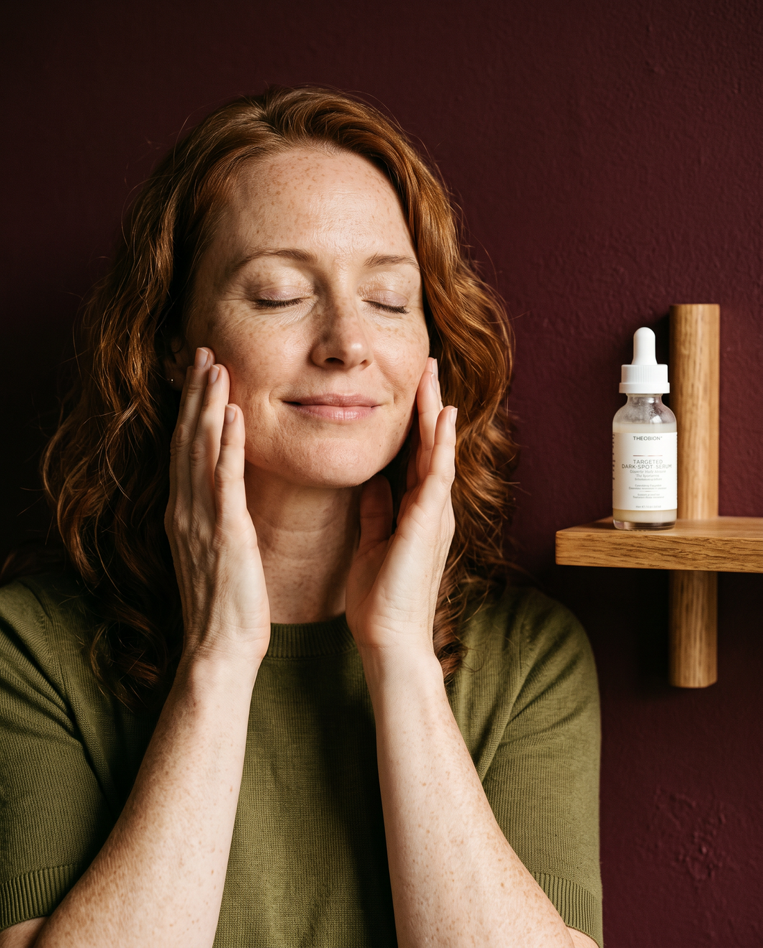 Woman with freckles smiling with fingertips on her cheekbones
